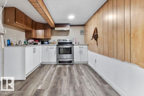 Modern stainless steel range with overhead ventilation, complemented by white lower cabinetry and light wood-finish upper cabinets - 712 Lee Ridge Road, Edmonton, AB 