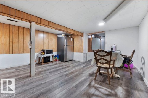 Spacious lower-level area featuring wood-finish flooring, wood paneling with white wainscoting, and a drop ceiling - 712 Lee Ridge Road, Edmonton, AB 