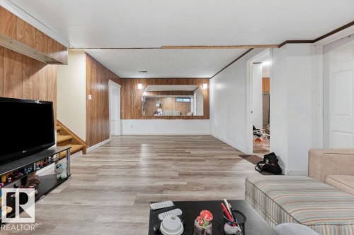 Spacious room featuring wood-finish paneling, light wood-finish flooring, and white painted walls - 712 Lee Ridge Road, Edmonton, AB 