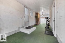 Covered exterior walkway featuring textured wall finish, a screen door entry, and an overhead light fixture - 