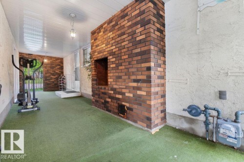 Covered outdoor area featuring a prominent brick column with a built-in recess, artificial turf flooring, and a white paneled ceiling with a hanging light fixture - 712 Lee Ridge Road, Edmonton, AB 
