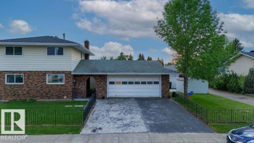 Two-story residence featuring brick and siding exterior, an attached garage with a paved driveway, and a front lawn with a decorative iron fence - 712 Lee Ridge Road, Edmonton, AB 