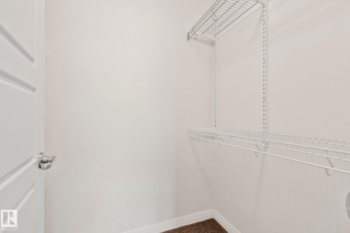 Closet featuring white wire shelving, a white paneled door with polished chrome hardware, and brown carpet flooring - 217 2588 Anderson Way, Edmonton, AB 