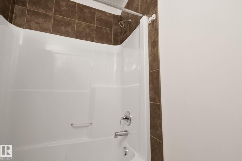 White tub and shower combination with chrome fixtures and a grab bar - 217 2588 Anderson Way, Edmonton, AB 