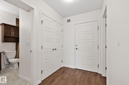 Entryway featuring wood-finish flooring, white paneled doors, and clean white walls - 217 2588 Anderson Way, Edmonton, AB 