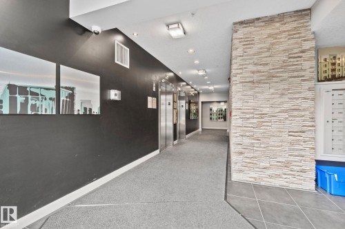 Hallway featuring stacked stone wall accents, dark painted walls, and recessed lighting - 217 2588 Anderson Way, Edmonton, AB 