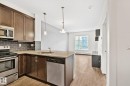 Kitchen featuring wood cabinetry, stainless steel appliances, a subway tile backsplash, and a breakfast bar - 217 2588 Anderson Way, Edmonton, AB 