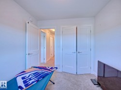 Bedroom featuring neutral carpeting, white walls, a single panel interior door, and a bi-fold closet door - 