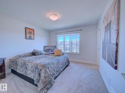 Carpeted bedroom featuring a large window, a ceiling-mounted light fixture, white walls, and white trim - 