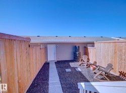 Fenced outdoor space featuring a paved walkway, dark ground cover, and a rear entry door - 