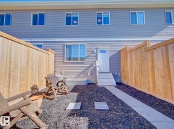 Private fenced outdoor space featuring a textured gray siding exterior, an exterior door with steps, and a paved pathway - 