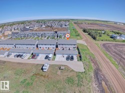 Aerial view of a multi-unit residential property, featuring multiple attached garages, individual fenced yards, and a paved parking area - 