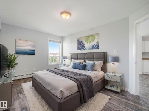 Bedroom featuring wood-finish flooring, a contemporary ceiling light fixture, and a large window - 2406 320 Clareview Station Drive, Edmonton, AB 