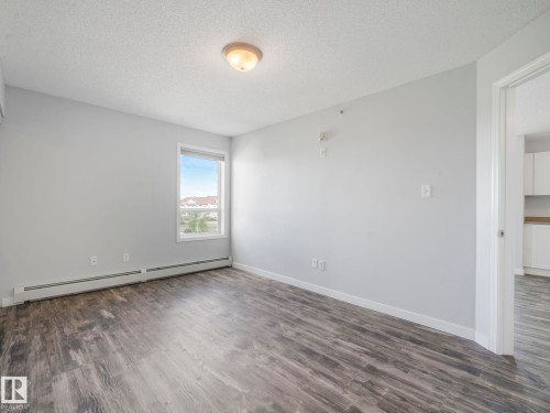 Spacious interior room with wood-finish flooring, light grey walls, and white trim - 2406 320 Clareview Station Drive, Edmonton, AB 