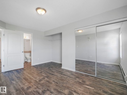 Room featuring wood-finish flooring, light grey walls, and a ceiling-mounted light fixture - 2406 320 Clareview Station Drive, Edmonton, AB 