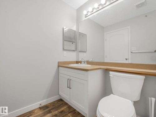 Bathroom featuring a white vanity cabinet with brushed nickel pulls, an integrated sink, and a light-toned countertop - 2406 320 Clareview Station Drive, Edmonton, AB 