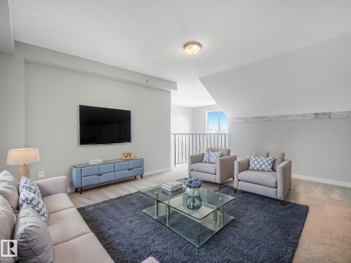 Spacious living area featuring light-toned walls, wood-finish flooring, and a contemporary railing system - 2406 320 Clareview Station Drive, Edmonton, AB 