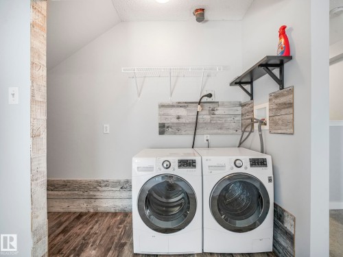 Dedicated laundry area featuring wood-finish flooring, light gray wall paint, and a sloped ceiling - 2406 320 Clareview Station Drive, Edmonton, AB 