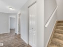 Interior hallway featuring wood-finish flooring, light grey walls, and a carpeted staircase with a white handrail - 2406 320 Clareview Station Drive, Edmonton, AB 