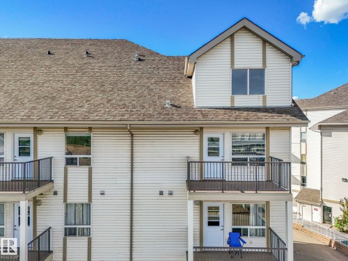 Multi-level building exterior featuring light-colored siding, dark shingle roofing, and multiple balconies with dark railings - 2406 320 Clareview Station Drive, Edmonton, AB 