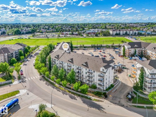 Multi-story building featuring white siding with dark trim, multiple private balconies, and a large communal parking area - 2406 320 Clareview Station Drive, Edmonton, AB 