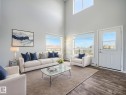 Living area featuring high ceilings, large windows, wood-finish flooring, and a white paneled door with glass insert - 2406 320 Clareview Station Drive, Edmonton, AB 