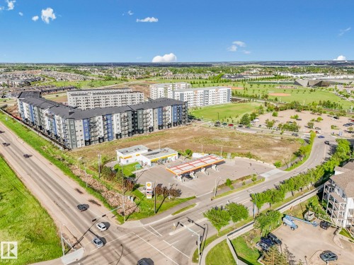 Aerial perspective showcasing multi-story residential buildings with balconies, extensive green spaces, and a commercial gas station - 2406 320 Clareview Station Drive, Edmonton, AB 