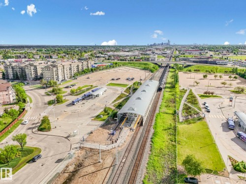 Aerial perspective showcasing a multi-story residential building, a light rail transit station with covered platforms, a bus terminal, and expansive parking areas - 2406 320 Clareview Station Drive, Edmonton, AB 