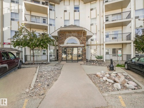 Building exterior featuring a prominent stone facade entrance with an arched glass doorway - 2406 320 Clareview Station Drive, Edmonton, AB 