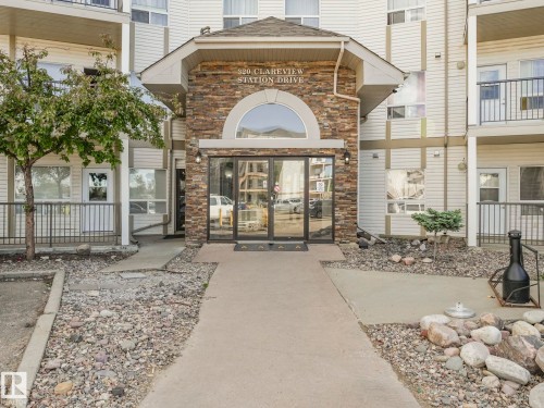 Building entrance featuring a stone-clad facade and a prominent arched window above glass double doors - 2406 320 Clareview Station Drive, Edmonton, AB 