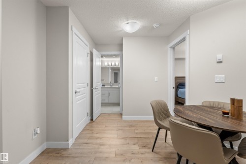 Light wood-finish flooring throughout, complemented by white baseboards and neutral wall tones - 210 2229 44 Avenue, Edmonton, AB 
