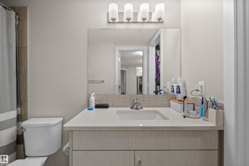 Vanity featuring a solid surface countertop with an integrated sink and chrome faucet - 210 2229 44 Avenue, Edmonton, AB 