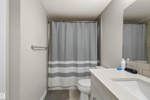 Bathroom featuring a vanity with an integrated sink, light-toned countertop, and wood-finish cabinetry - 210 2229 44 Avenue, Edmonton, AB 