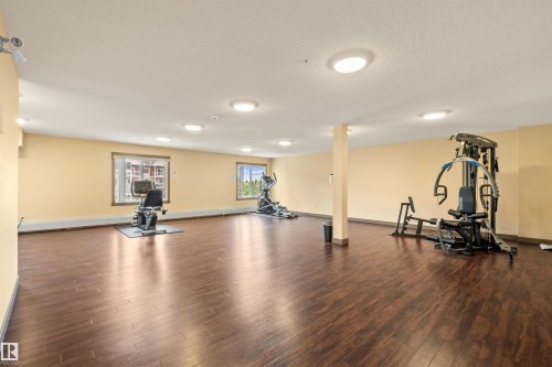 Spacious fitness area featuring dark wood-finish flooring, recessed lighting, and multiple windows - 210 2229 44 Avenue, Edmonton, AB 
