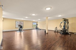 Spacious fitness area featuring dark wood-finish flooring, recessed lighting, and multiple windows - 