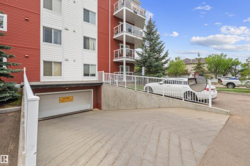 Concrete ramp leading to an underground parking garage with a white roll-up door - 210 2229 44 Avenue, Edmonton, AB 