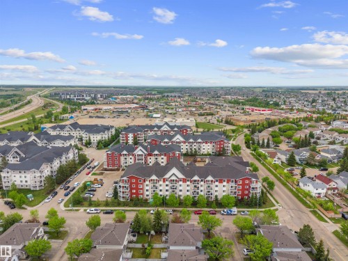 Aerial perspective showcasing multiple residential buildings, including multi-story structures with red and white exteriors, and single-family homes with dark roofs - 210 2229 44 Avenue, Edmonton, AB 