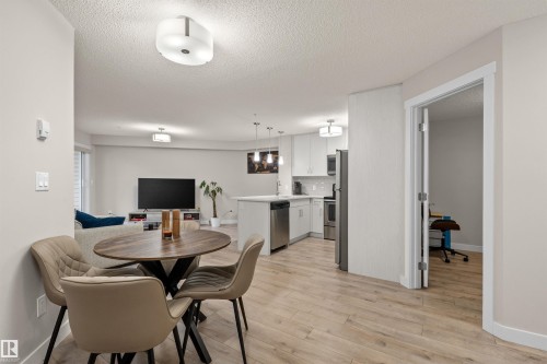 Open-concept living space featuring wood-finish flooring, a contemporary kitchen with stainless steel appliances, and a dedicated dining area - 210 2229 44 Avenue, Edmonton, AB 