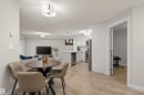 Open-concept living space featuring wood-finish flooring, a contemporary kitchen with stainless steel appliances, and a dedicated dining area - 210 2229 44 Avenue, Edmonton, AB 