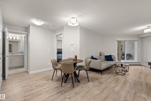 Open-concept living space featuring wood-finish flooring, recessed lighting, and a sliding glass door to a private balcony - 210 2229 44 Avenue, Edmonton, AB 