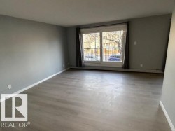 Spacious room featuring light gray walls, wood-finish flooring, and white baseboards - 