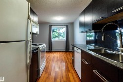 Galley kitchen featuring wood-finish flooring, dark cabinetry, and light-colored walls - 