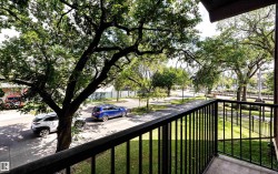 Balcony with black metal railings and a concrete floor, offering an elevated perspective of the surrounding area - 