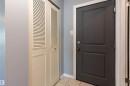 Entryway featuring a paneled door with brass hardware, tile flooring, and a louvered bi-fold closet door - 202 10740 105 Street, Edmonton, AB 
