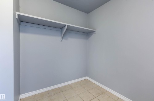 Interior storage space featuring a built-in shelving unit, light gray wall paint, and floor tiling - 202 10740 105 Street, Edmonton, AB 