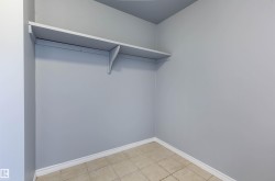 Interior storage space featuring a built-in shelving unit, light gray wall paint, and floor tiling - 