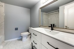 Bathroom featuring a white vanity with black hardware, a rectangular undermount sink, and a black faucet - 