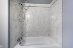 Bathtub with white subway tile surround featuring gray veining - 