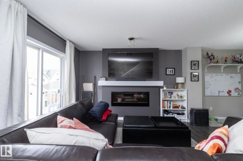 Living area featuring a built-in fireplace, a white mantel, and wood-finish flooring - 46 4050 Savaryn Drive, Edmonton, AB 