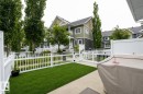 Private patio area with artificial turf, white picket fencing, and concrete hardscaping - 46 4050 Savaryn Drive, Edmonton, AB 